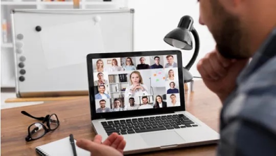Imagen de un hombre y la pantalla de un computador, en reunión virtual