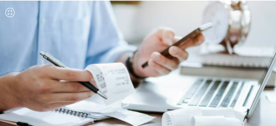 Imagen de persona con recibo en la mano y celular en otra mano